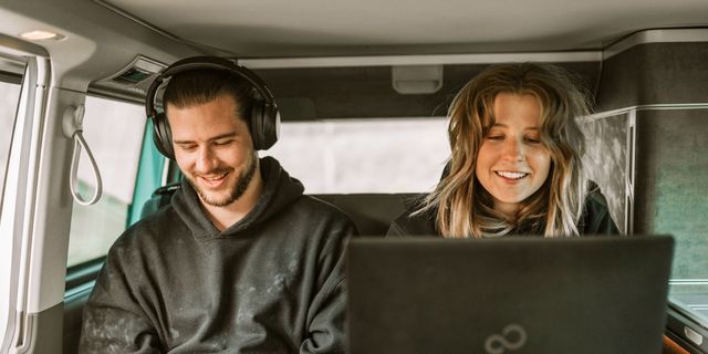 Zwei CamperBoys Reisende hören Musik und arbeiten im Camper